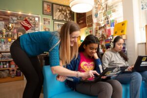 Female English teacher with two female students on computers